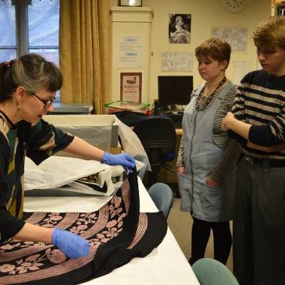 Young people watching a demonstration of folding a fabric artefact